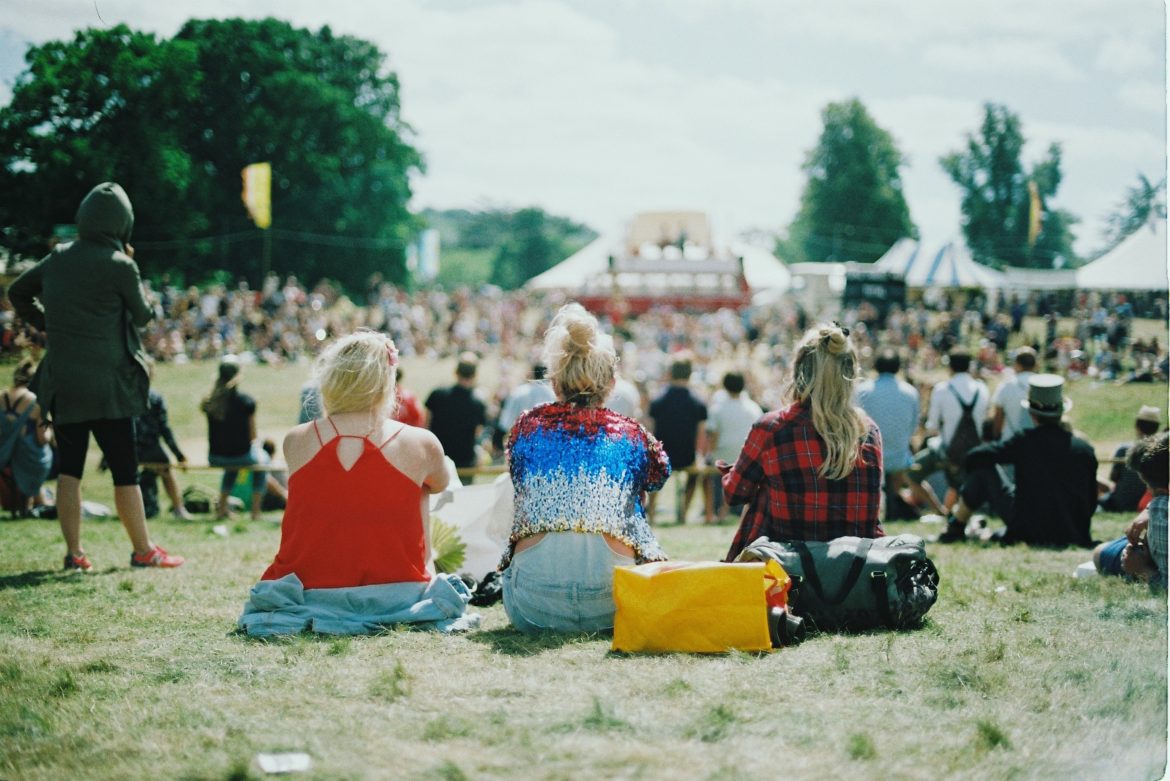 Three women sitting in a park at a music festival.