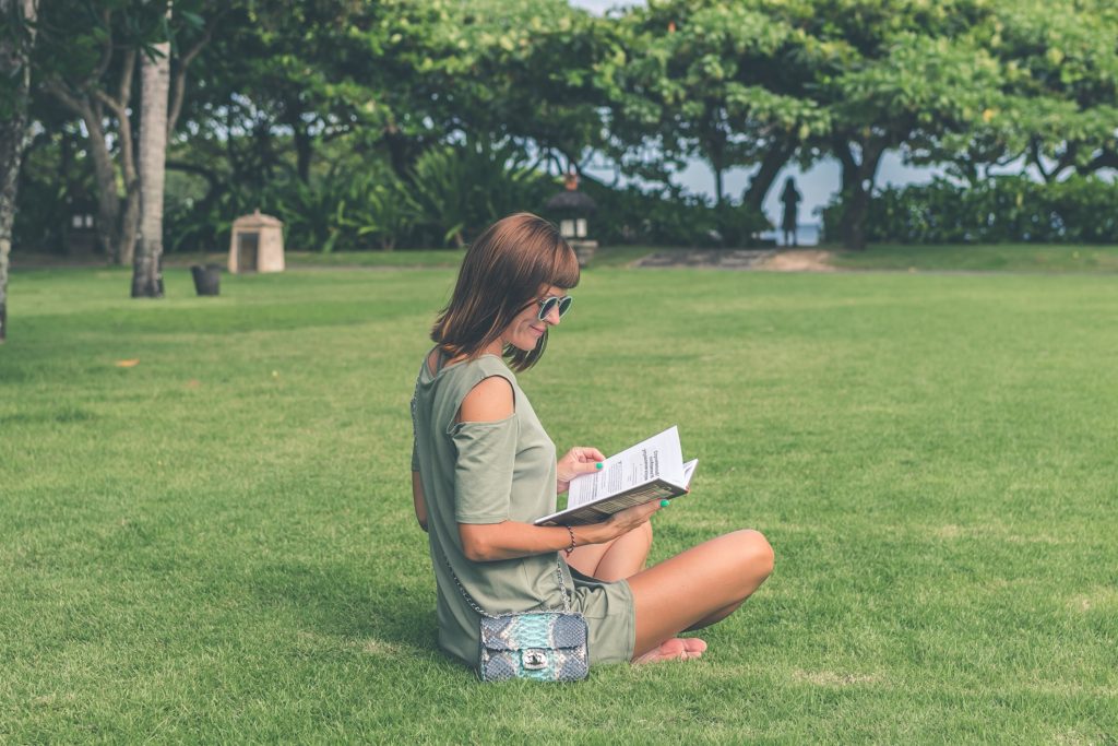 Woman reading a book in the middle of the park.