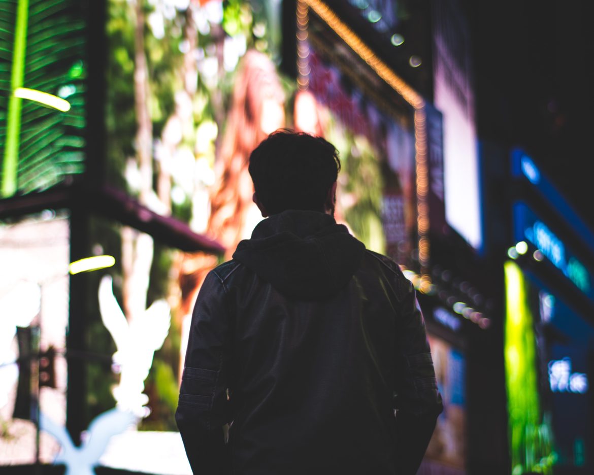 Man standing in front of New York City billboards at night.