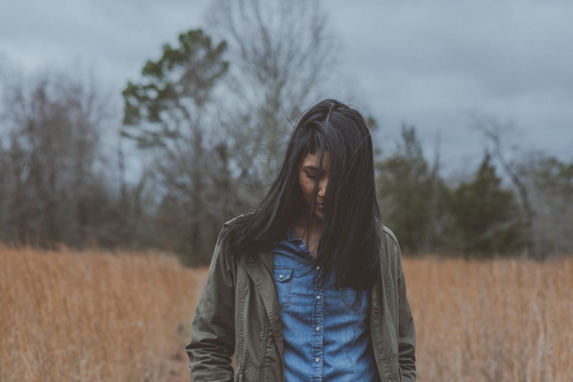 A woman standing in a field on a cloudy day.